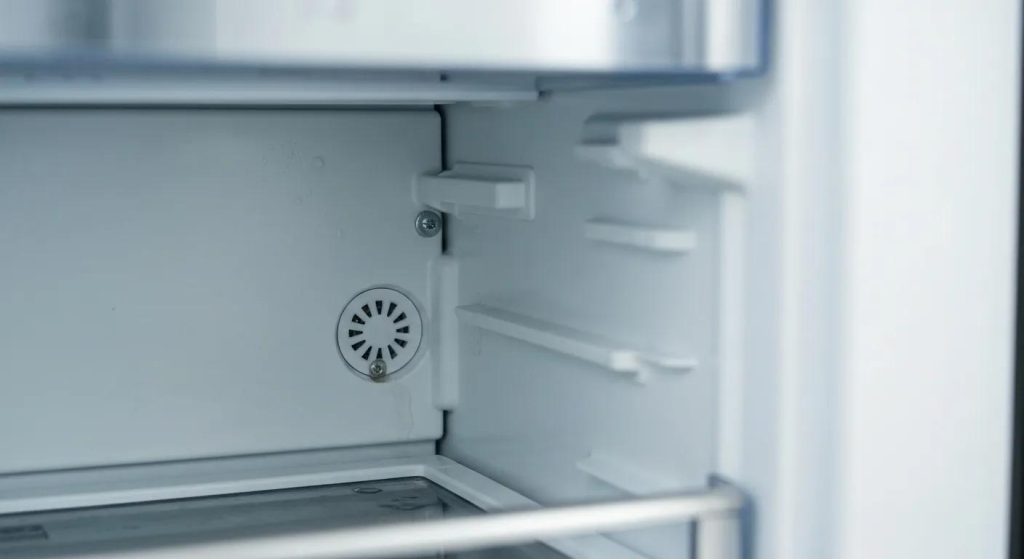 A close-up view of a refrigerator's defrost drain being examined for signs of water leaks in a Charlotte, NC home.